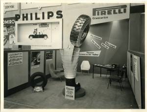<p>Panoramica dello stand Pirelli allestito al Salone Internazionale dell'Automobile di Parigi del 1956. In primo piano la sezione ingrandita di una carcassa del pneumatico Grancarico . Sullo sfondo una gigantografia del pneumatico con pannelli che ne pubblicizzano le qualità.</p>