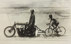 La fotografia riprende un momento dell'allenamento di un corridore: l'allenatore Manera è seduto su una moto, alla quale è attaccata la bicicletta con il corridore