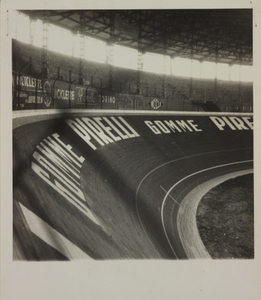 La fotografia riprende la scritta gomme Pirelli posta su una curva del Velodromo: sopra di essa si vedono gli striscioni pubblicitari di case produttrici di biciclette
