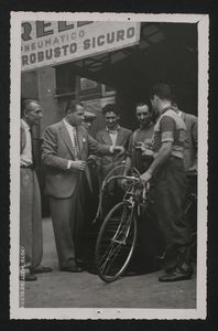 Distribuzione dei tubolari presso La Gazzetta dello Sport: un corridore  che ha ricevuto i tubolari, insieme ad altri uomini, uno dei quali è Alfredo Binda