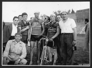 Un gruppo di persone al Velodromo Giovanni Monti: tra di essi vi è il vincitore della corsa, insieme al compagno di squadra e a un corridore di un'altra società ciclistica