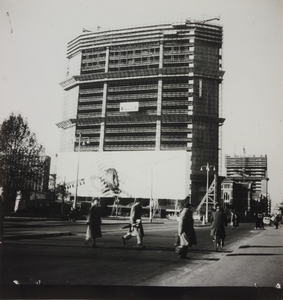 Veduta del grattacielo Pirelli in costruzione: l'edificio ha superato il ventesimo piano. Manifesto pubblicitario dello pneumatico Inverno