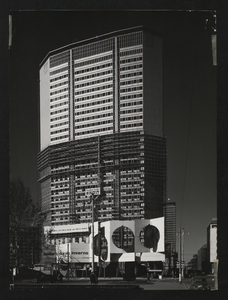 Il Centro Pirelli in costruzione: il grattacielo, completo nei piani superiori, ripreso da piazza Duca d'Aosta. È visibile un'installazione pubblicitaria progettata da Pino Tovaglia e realizzata dalla I.P.I.: su una parete di 440 metri quadrati di superficie, a quinte, sono inserite tre sagome di pneumatici di 6 metri di altezza che ruotano intorno al proprio asse, azionate da un motore elettrico. L'immagine è stata pubblicata da Fatti e Notizie, anno X, febbraio-marzo 1959, p. 16