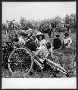 Adulti e bambini seduti in un campo: in primo piano sono visibili le biciclette