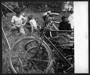 Donne e uomini in un campo: in primo piano sono visibili le biciclette