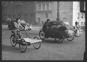 Il passaggio di due furgoncini a pedali in una strada cittadina