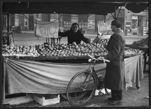 Un uomo con bicicletta davanti a un banco di frutta