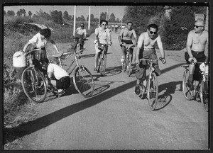 Un gruppo di persone in bicicletta in una strada di campagna