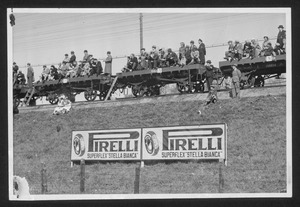 Spettatori osservano la corsa dai carrelli di un treno: sulla collina pubblicità Pirelli Superflex Stella Bianca