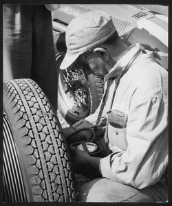 Un tecnico del Servizio Corse Pirelli controlla la pressione degli pneumatici: l'immagine è stata pubblicata dalla rivista Pirelli (anno III, n. 5, settembre-ottobre 1950, p. 29)