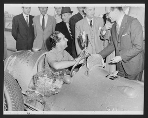 Il pilota Alberto Ascari riceve la coppa dopo la vittoria nella prima edizione del Gran Premio di Modena: l'immagine è stata pubblicata dalla rivista Pirelli (anno III, n. 3, maggio-giugno 1950, p. 14)