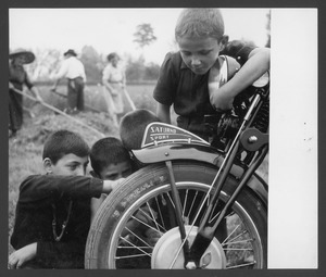 Alcuni bambini osservano una motocicletta Gilera Saturno Sport equipaggiata con pneumatici Pirelli: sullo sfondo, adulti al lavoro nei campi