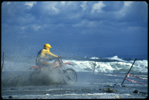 Il pilota Maurizio Dolce durante una gara motociclistica, probabilmente della specialità motocross, disputatasi in riva al mare