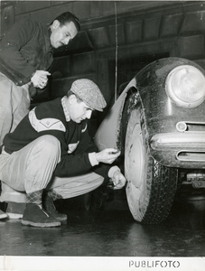 Due uomini effettuano un controllo del pneumatico anteriore destro di una macchina durante il Rally di Montecarlo del 1952