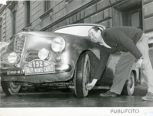 Il principe Raimondo Lanza di Trabia controlla il pneumatico anteriore sinistro dell'automobile Alfa Romeo 1900 (n. 192, targa 174969 MI) durante il controllo di Milano del Rally di Montecarlo 1952