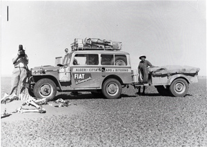 L'operatore cinematografico della Incom Aldo Pennelli, fermo con una donna accato alla Fiat Campagnola usata durante il Raid Algeri - Città del Capo del 1952, filma dei resti ossei