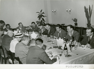 Tredici commensali a una tavola durante il Raid Algeri-Città del Capo del 1952. Si riconosce il pilota Paolo Butti.