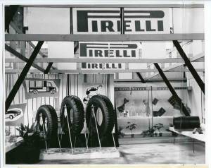 Veduta dello stand Pirelli. Esposizione di pneumatici. In alto: insegne pubblicitarie Pirelli.