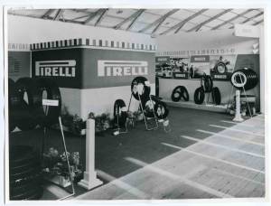 Veduta generale dello stand Pirelli. Esposizione di pneumatici. Alle pareti manifesti pubblicitari e pannelli fotografici di alcune importanti vittorie sportive.