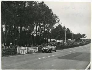 José Froilán González su Ferrari imbocca il rettilineo dell'arrivo alla 24 Ore di Le Mans del 12 giugno 1954. Lungo il guard rail è visibile uno striscione pubblicitario PNEU PIRELLI