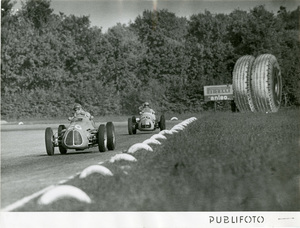 Il pilota José Froilán González percorre il Circuito di Monza su Maserati n. 26 al Gran Premio d'Italia del 7 settembre 1952. Sullo sfondo un cartellone pubblicitario Pirelli Anteo.