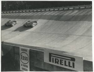 Stirling Moss su Mercedes n. 16 seguito dal compagno di scuderia Juan Manuel Fangio (n. 18) sulla pista dell'Autodromo di Monza, durante il Gran Premio d'Italia dell'11 settembre 1955. In primo piano, due insegne pubblicitarie Esso e Pirelli.