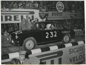 Il pilota Santo Ciocca su Alfa Romeo Giulietta Sprint n. 232 gommata Pirelli, sulla pedana di partenza della Mille Miglia del 30 aprile-1° maggio 1955. Sono visibili delle pubblicità Pirelli sulla pedana e sugli spalti.
