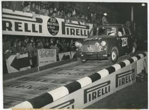Il pilota Alfranco Pagani su Fiat 1100/103 n. 2251 sulla pedana di partenza della Mille Miglia del 30 aprile-1° maggio 1955. Sono visibili delle pubblicità Pirelli sulla pedana e sugli spalti.