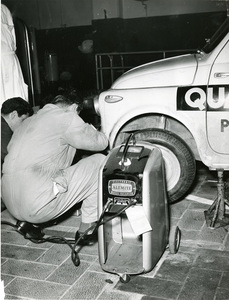 Un meccanico controlla il pneumatico anteriore di una Fiat 500 con un bilanciatore Alemite durante il Raid Fiat 500 disputatosi tra il 18 marzo e l'8 giugno 1958